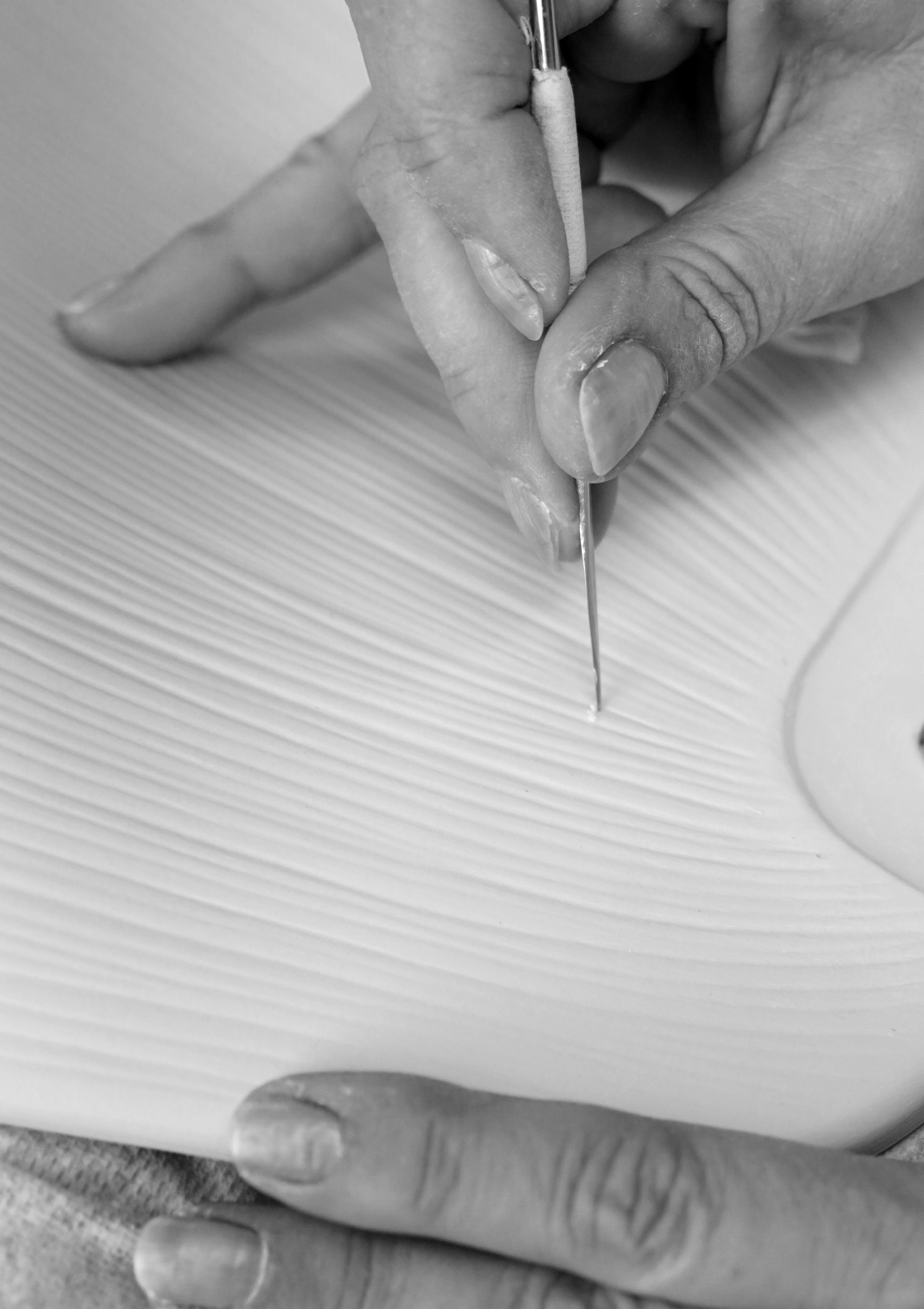 A close-up of a hand carving the pattern in one part of the lamp.